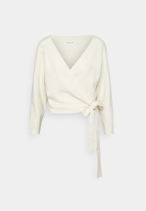 Pull cache-cœur de couleur crème avec manches longues et un nœud à nouer sur le côté, avec un décolleté en V profond.