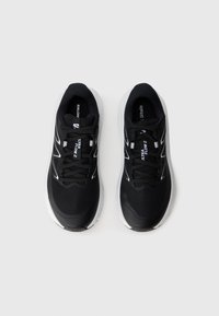 Baskets de sport noires avec tissu en maille, col rembourré, accents blancs, lacets traditionnels et semelle texturée pour une meilleure adhérence.
