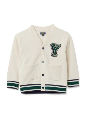 Cremiger Kinder-Cardigan mit schwarzen Knöpfen, zwei vorderen Taschen, grün-schwarzen gestreiften Bündchen und Saum sowie einem grünen „Y“-Patch im College-Stil auf der Brust.
