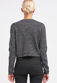 Cropped sweater in black and white knit, featuring long sleeves and a textured pattern. Back view shows ribbed fabric detail.