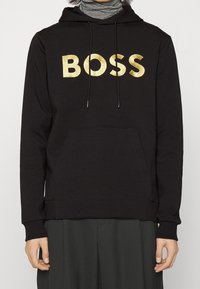 Felpa nera con lettering dorato "BOSS", coulisse e tasca frontale. Tessuto morbido, vestibilità regolare, polsini e orlo a coste per un comfort aggiuntivo.