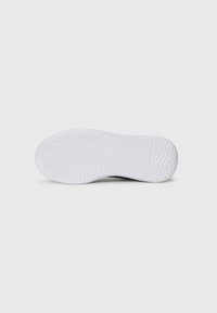 White rubber shoe sole with a textured pattern; features a rounded shape and pronounced treads for grip and stability.