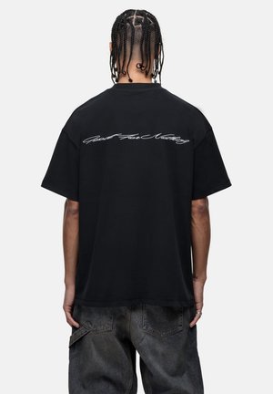 Zwarte katoenen t-shirt, korte mouwen, losse pasvorm. Bevat witte cursieve tekst "Good For Nothing" op de bovenrug. Getextureerde stof.