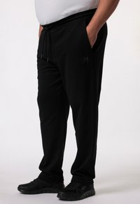 Schwarze Jogginghose mit elastischem Bund, Kordelzug und Seitentaschen. Hergestellt aus weichem Stoff mit einem subtilen Logo auf dem linken Oberschenkel.