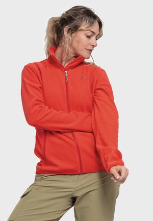 Red fleece jacket with a high collar, full zip, and zippered pockets. Features a logo in grey on the left chest and long sleeves.