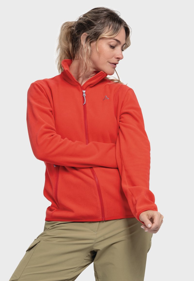 Red fleece jacket with a high collar, full zip, and zippered pockets. Features a logo in grey on the left chest and long sleeves.