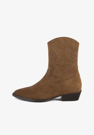 Bruine suède enkellaars met spitse neus, decoratieve stiksels en een lage blokhak. Gladde textuur, hoogte tot halverwege de kuit en geen zichtbare hardware.