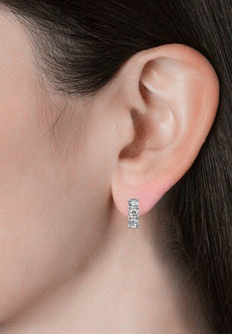 Orecchini rettangolari argento con tre gemme collegate, che presentano un design sfaccettato e scintillante. Indossati all'orecchio di un modello.