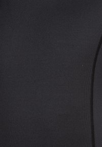 Musta venyvä kangas, jossa on sileä pinta. Hieman kiiltävä pinta ja vastakkaistyyppinen, teksturoitu paneeli toisella puolella. Minimalistinen muotoilu.