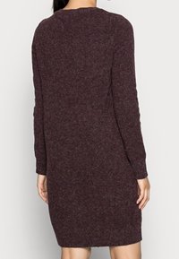 Långärmad tröjdress i en djup burgundyröd färg, med ett texturerat stickat tyg och en avslappnad passform som slutar ovanför knäet.