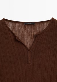 Hnědý rebrovaný pletený top s výstřihem do V a tříknopkovou légou. Na štítku je na černém pozadí nápis "Massimo Dutti".