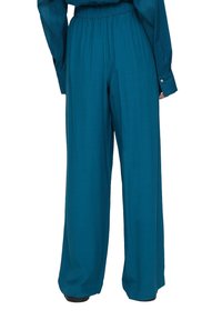 Vida byxor i en teal färg, tillverkade av ett mjukt tyg, med elastisk midja och enkla sömnadsdetaljer.