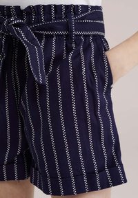 Jūras spēku šorti ar baltām punktētām vertikālām svītrām, elastīga josta ar saitīšu, un sānu kabatām ar salocītu malējumu.