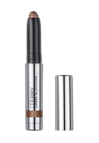 Metallischer silberner und schwarzer Behälter mit einer abgerundeten bronzefarbenen Spitze, beschriftet mit "Ombre Blackstar." Der Deckel ist getrennt, was das Creme-Stick-Format offenbart.