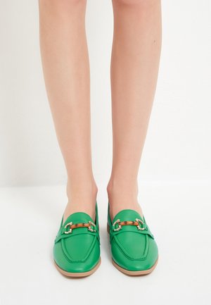 Grüne Loafers aus Leder mit glatter Textur. Verfügt über eine dekorative Schnalle in Goldoptik und eine tanfarbene Sohle. Klassische Form.