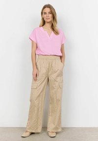 Lys rosa bomulds T-shirt med V-hals, parret med beige stribede bredbenede bukser, der har forfinede lommer og en elastisk talje. Beige sko fuldender outfittet.