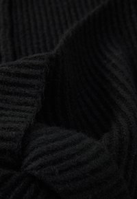 Tejido negro de punto con textura acanalada. Suave, esponjoso y grueso, mostrando un patrón oscuro y monocromático que enfatiza la profundidad.
