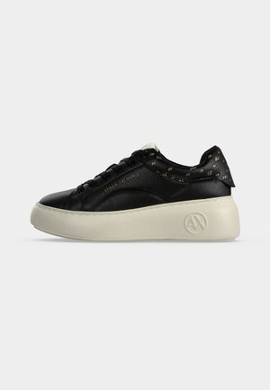 Zwarte leren sneaker met dikke witte zool, gouden "ARMANI EXCHANGE" tekst aan de zijkant en gouden "AX" logopatroon op de hiel en zoolrand.
