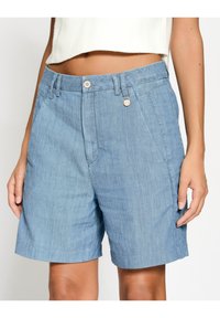 Svetle modré denimové šortky s rovnou siluetou, předními kapsami a zapínáním na knoflík. Měkká textura, ležérní design a prošívané detaily.