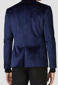 Námořnický sametový blazer s hladkou texturou, jediným ventilem na zadní straně a černými knoflíkovými akcenty na rukávech. Vysoký límcový design.