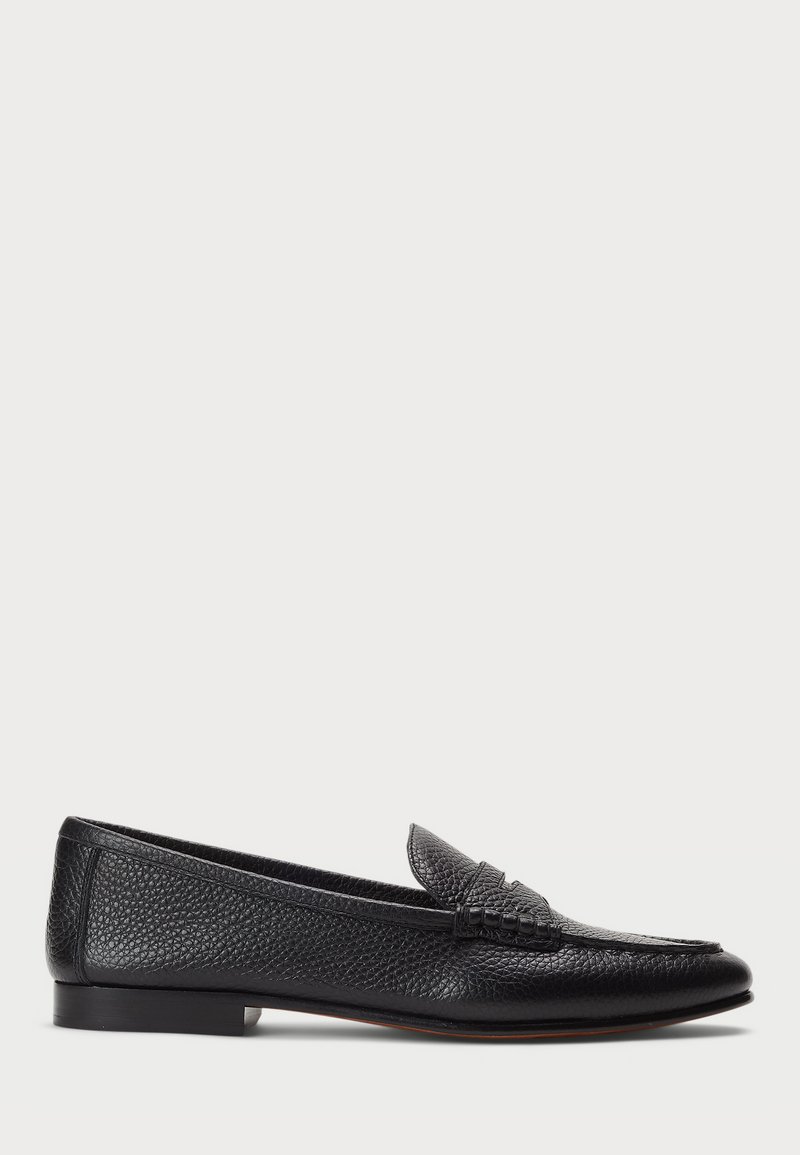 Black leather loafer with a textured finish, featuring a decorative strap and flat heel. Sleek, minimal design with rounded toe.