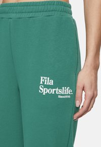 Vihreät puuvillateksarit, joissa on joustava vyötärö. Lahkeessa on valkoisesti painettu logo "Fila Sportslife" ja teksti "Since 1974".
