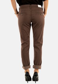 Pantaloni marroni realizzati in un tessuto morbido, con una vestibilità slim, orli arrotolati e tasche posteriori decorative con un piccolo accento a forma di cuore.