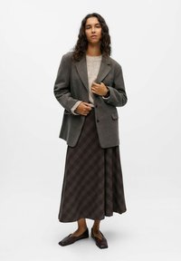 Grau wolle Blazer mit Reverskragen, cremefarbener Strickpullover und braunem kariertem Maxirock. Kombiniert mit dunkelbraunen flachen Schuhen.