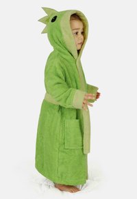 Grüner Kapuzenbademantel aus plüschigem Material mit strukturierter Oberfläche. Verfügt über drachenartige Details, einen beigen Besatz und eine Fronttasche.