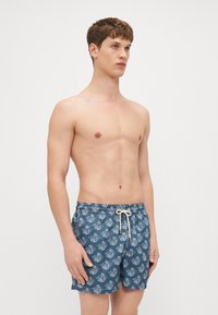 Blaue gemusterte Badeshorts mit weißen Blumenmotiven, elastischem Bund und Kordelzug. Der Stoff wirkt leicht und hat eine glatte Textur.