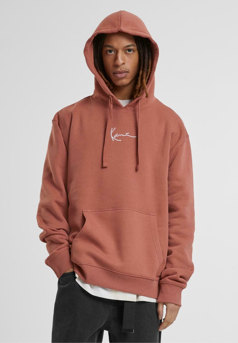 Hætte sweatshirt i støvet rose farve, lavet af blødt stof. Har frontlomme, hvid logo broderi og ribbestrikkede cuffs og kant.