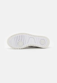 Fehér sneaker talp texturált gumival, kör alakú részletekkel és hullámos mintázattal. Tiszta dizájn és tartós anyag sima felülettel.