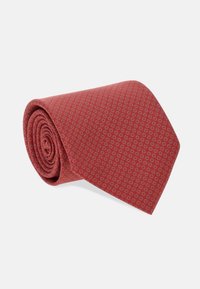 Czerwona krawatka wykonana z teksturowanej tkaniny, z subtelnym kwiatowym wzorem w jasnoszarym kolorze. Zwiń stworzony do ekspozycji, z ostro zakończonym końcem.
