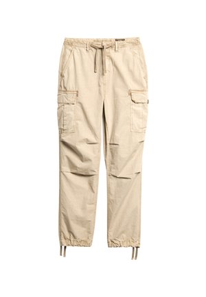 Beige cargobroek gemaakt van lichtgewicht stof. Voorzien van een elastische tailleband, trekkoord en meerdere zijzakken met taps toelopende pijpen.