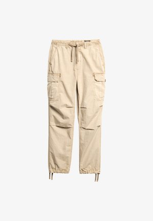 Beige cargobroek gemaakt van lichtgewicht stof. Voorzien van een elastische tailleband, trekkoord en meerdere zijzakken met taps toelopende pijpen.