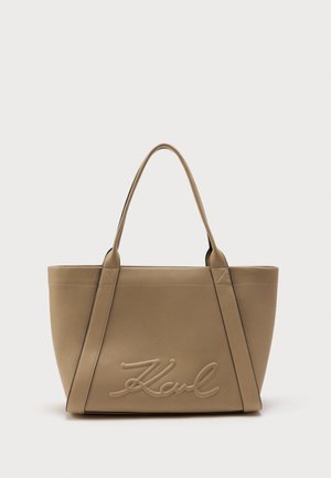 Beige rectangular tote bag with dual handles and raised stitched script "Karl" on front, set against a plain white background.