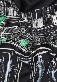 Tessuto di seta nera con schizzi bianchi e verdi di figure della moda e vetrine, con il testo "Karl Lagerfeld" in accenti blu.