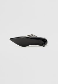 Musta lakattu nahka stiletto-korkokenkä, jossa on terävä kärki ja koristeellinen hopeanvärinen yksityiskohta ylhäällä. Sileä pinta, tyylikäs muotoilu.