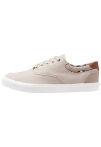 Beige canvas sneakers med vit gummisula, rund tå och snörning. Brunt läderdetalj på hälen, randig innersula.