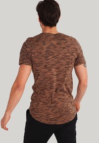 Braunes Kurzarm-T-Shirt mit strukturiertem, meliertem Muster, tailliertem Schnitt und abgerundetem Saum, von hinten betrachtet.