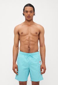 Shorts de bain bleu clair avec une taille élastique et un cordon de serrage. Présentent un détail logo sur le côté et une texture lisse et légère.