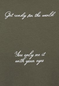 Tela de color verde oliva con textura acanalada que presenta dos frases en texto cursivo blanco: "Prepárate para el mundo" y "Solo lo ves con tus ojos."