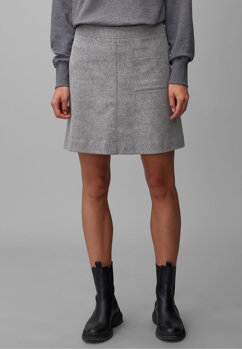 Jupon en mélange de laine gris avec une coupe droite, comportant une poche latérale et une finition texturée, associé à des bottines noires. 
