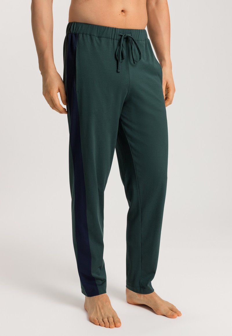 Groene sportbroek met een elastische tailleband en trekkoord, zijzakken en contrasterende navy zijstrepen. Zachte textuur en losse pasvorm.