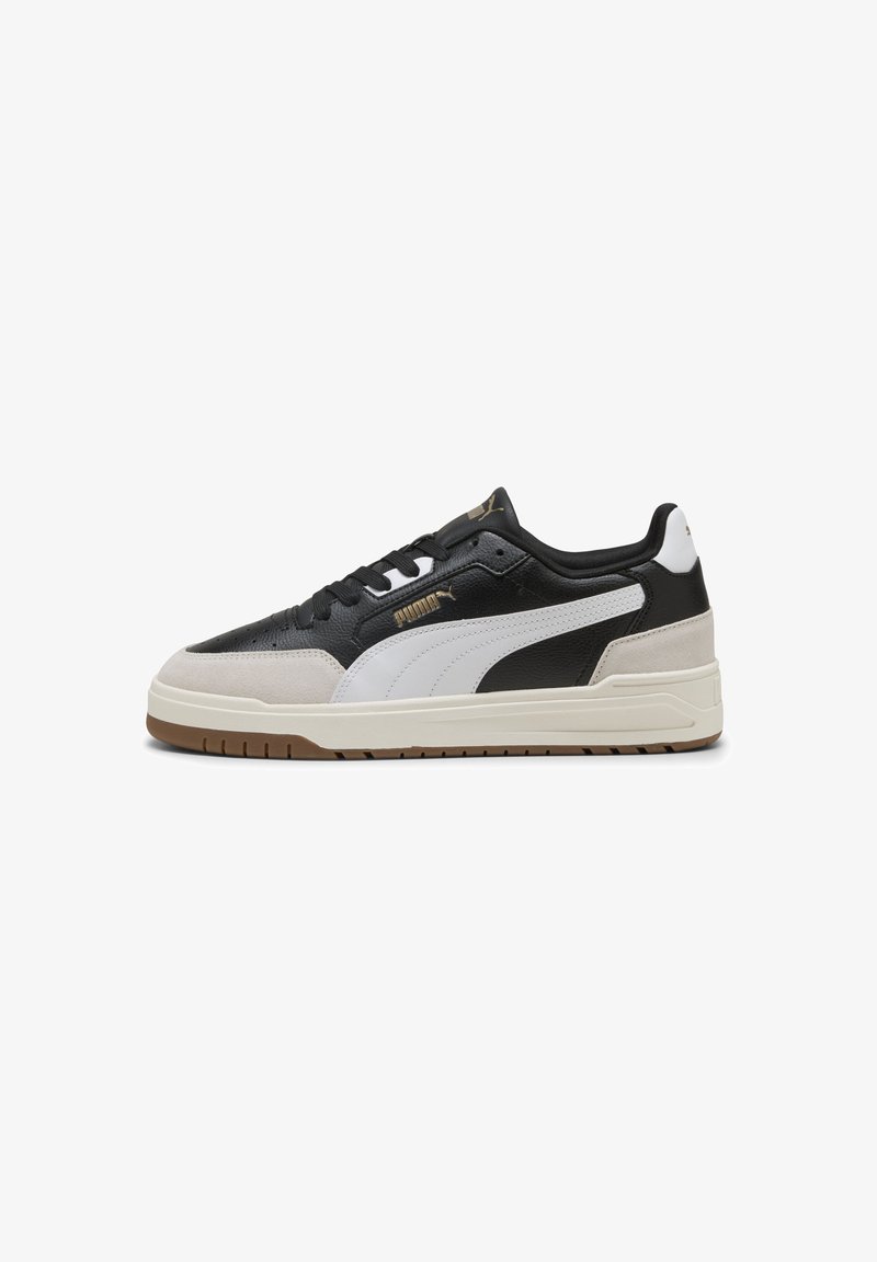 Adidași negri și albi, din materiale de nubuck și piele, cu talpă din cauciuc, sistem de închidere cu șireturi și accente de logo aurii.