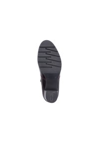 Semelle de chaussure en caoutchouc noir, présentant un motif de grip texturé avec des rainures et un talon contourné. Accents rouges le long du bord.