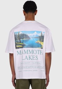 White cotton t-shirt featuring a landscape graphic with mountains and a lake on the back. Text reads "MAMMOTH LAKES" and additional details below.