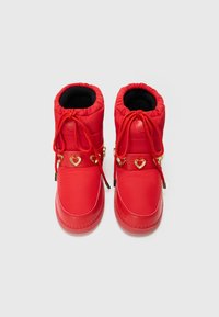Red waterproof boots with a padded design, rounded toe, elastic openings, and gold heart-shaped accents on a decorative strap. Black lining.