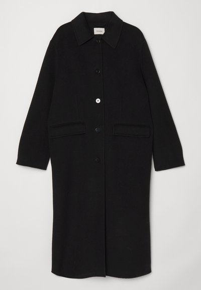 Casaco de lã preto com gola, botões frontais e dois grandes bolsos de chapa. Corte reto com mangas longas.