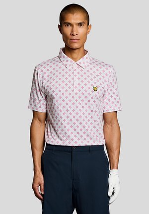 Mand iført en kortærmet polo med hvidt og lyserødt mønster, marineblå bukser og en hvid golfhandske på venstre hånd.